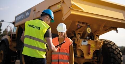 一名沃尔沃驾驶员培训讲师用平板电脑向面露微笑的学员展示反馈。