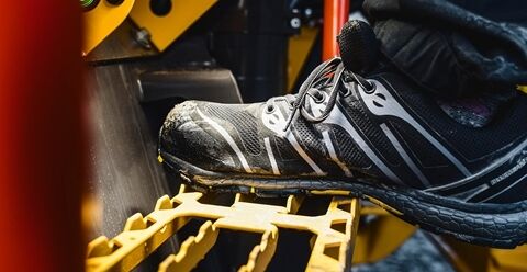 A shoe on the step of an articulated hauler as it enters the machine