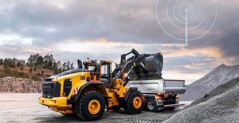 volvo wheel loader loading Volvo truck in a quarry. Connectivity graphic above them shows connection with CareTrack.