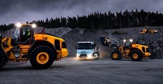Volvo L150 wheel loader and Volvo L180 wheel loader loading a Volvo FMX truck at night in a quarry