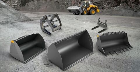 Buckets, grab and forks positioned in front of Volvo L180 wheel loader in a quarry