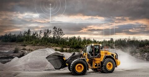 Volvo L220 wheel loader travelling through quarry. Connectivity graphic above it illustrates connection with CareTrack telematics