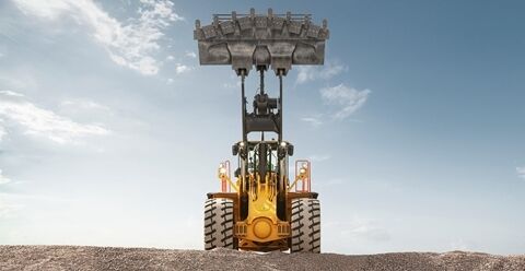 Low-angle view of a Volvo L350H loader lifting its bucket to its maximum height.